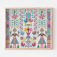 Colorful palestinian tatreez christmas cross stitch with two girls and folk art motifs in a wood frame