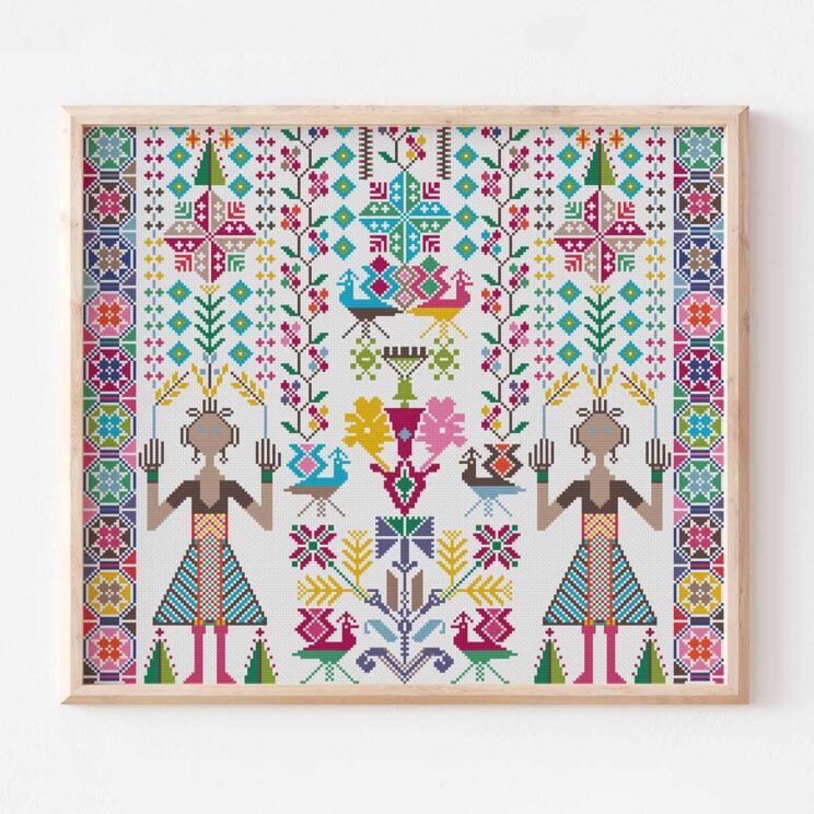Colorful palestinian tatreez christmas cross stitch with two girls and folk art motifs in a wood frame