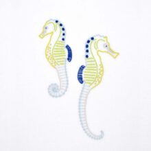 Anatomical Seahorses embroidery in blues and yellows on white fabric