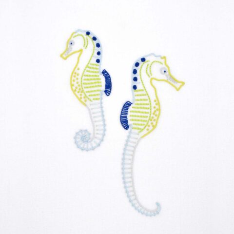 Anatomical Seahorses embroidery in blues and yellows on white fabric