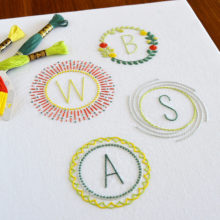 Four embroidered monograms of the letters B, W, S, and A stitched in red, yellow, and green