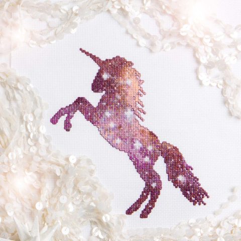 cross-stitch of a unicorn silhouette filled with a sparkling purple nebula