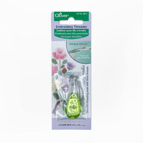 A green, plastic embroidery needle threader with a clear cap on a Clover branded hang card