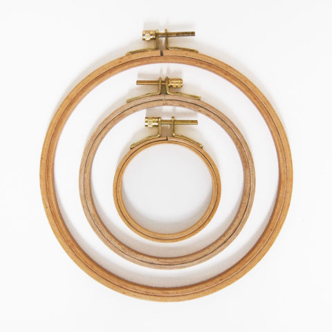 Three wooden embroidery hoops arranged concentrically on a white background