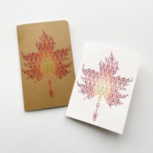 A blackwork leaf design in fall colors embroidered onto a kraft brown notebook cover and a white greeting card