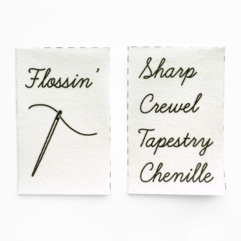 two pieces of printable stabilizer. The left one shows a picture of a threaded needle and the word "flossin'." The right one shows a stack of words for needle types: sharp, crewel, tapestry, and chenille.