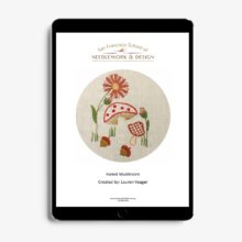 mushrooms, flowers, and acorns embroidered on natural linen displayed in a tablet