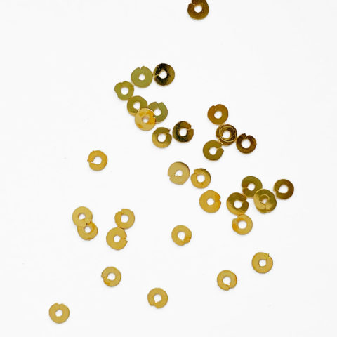 Gilt embroidery spangles scattered on a white background