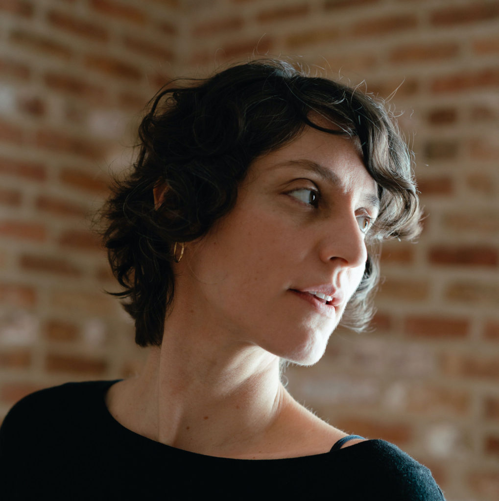 Headshot of embroidery artist Karen Barbé shown in three-quarter view in front of a brick wall