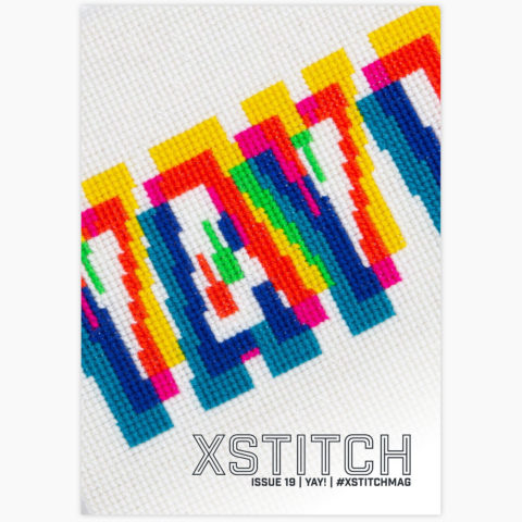 Cover of issue 19 of XStitch magazine showing the word YAY! stitched in glitchy rainbow colors like misaligned color filters
