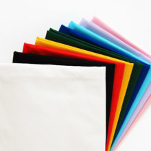 Folded squares of Kona cotton solids fabric arranged in a rainbow fan