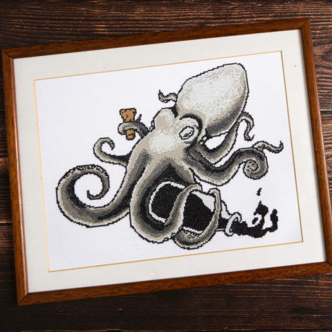 Framed cross-stitch of an octopus spilling a bottle of ink
