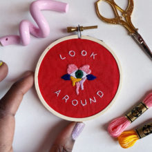 embroidery pattern composed of text that reads “Look around” and a colorful eye design accenting the text