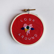 embroidery pattern composed of text that reads “Look around” and a colorful eye design accenting the text