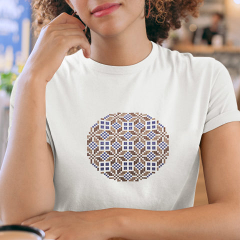 Geometric tatreez pattern stitched in a circle on a white t-shirt in indigo and brown