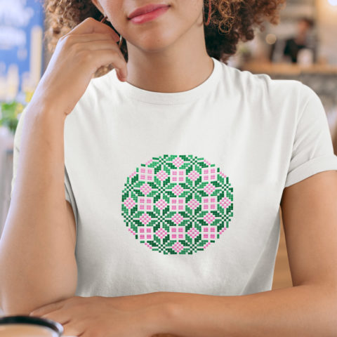 Geometric tatreez pattern stitched in a circle on a white t-shirt in pink and green