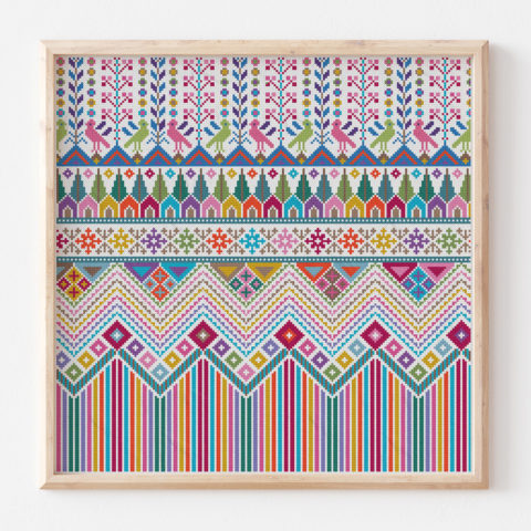 A colorful modern repeating Palestinian tatreez cross-stitch pattern in a blond wood frame depicting rows of striped mountaind, houses, trees, birds, and flowers