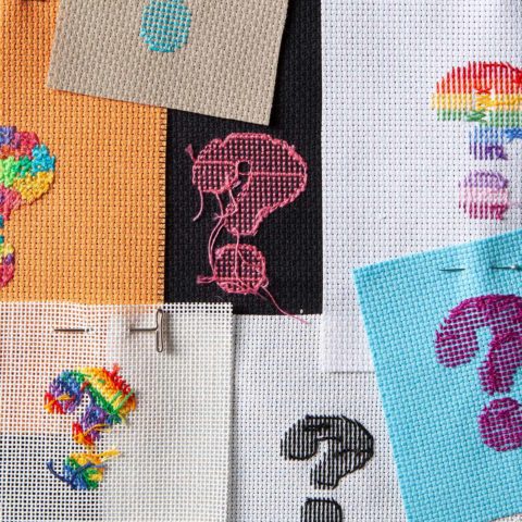 the fronts and back of cross-stitched question marks stitched in various colors on various backgrounds