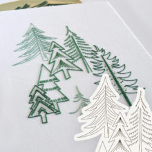 Outlines of various pine tree species embroidered on white fabric in different shades of green