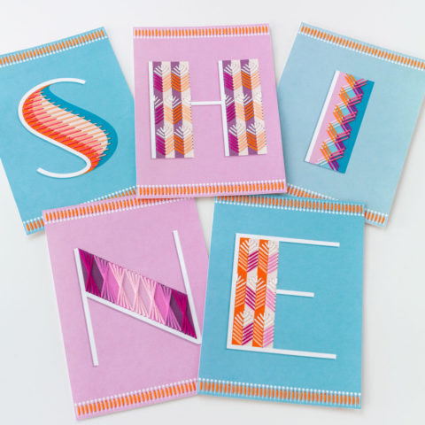 five postcards in blue and purple with one large letter embroidered on each to spell "shine"