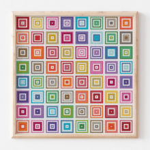 A decoelian tatreez cross stitch showing a grid of rainbow concentric squares in a wood frame