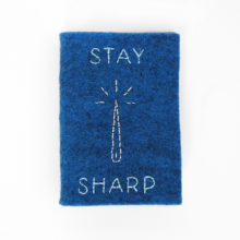 Blue felt needle book with the words stay sharp and a needle embroidered on the cover