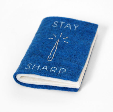 Blue felt needle book with the words stay sharp and a needle embroidered on the cover