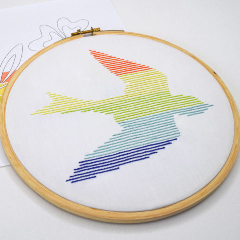Swift bird embroidered using rainbow parallel lines on white fabric in a hoop