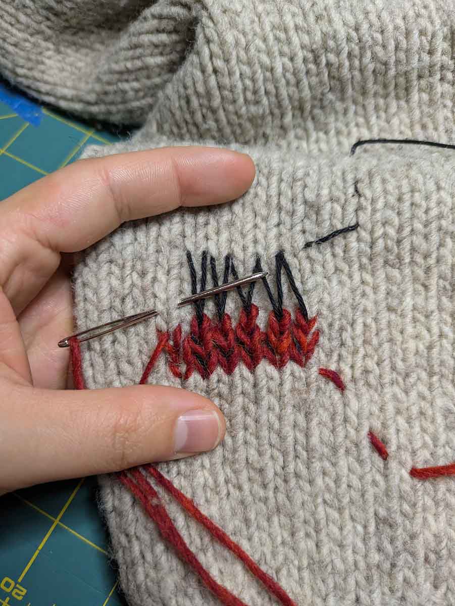 Swiss Darning with red thread on a beige sweater