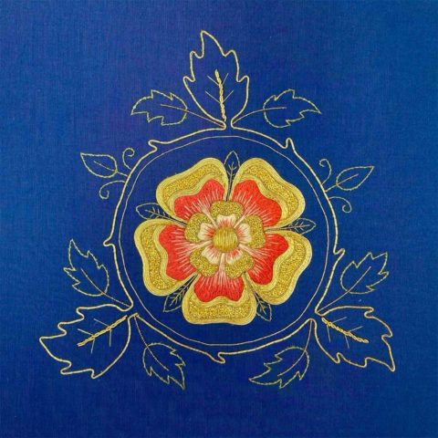 Tudor style rose embroidered in gold and red on royal blue silk