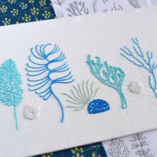 Various corals embroidered in blue and white on white fabric