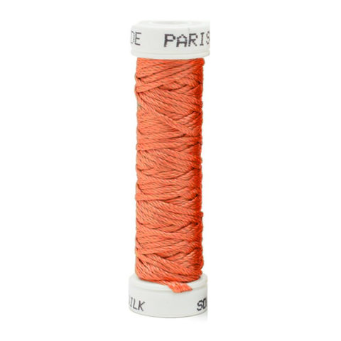 a spool of orange silk thread on a white background