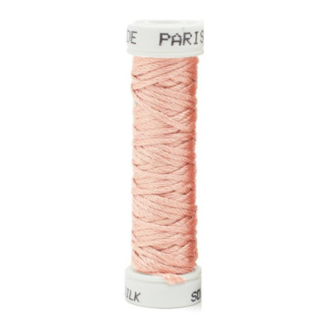 a spool of light pink silk thread on a white background