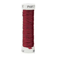a spool of dark red silk thread on a white background