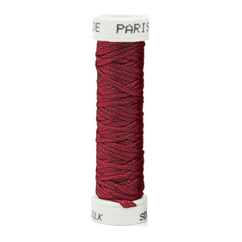 a spool of dark red silk thread on a white background