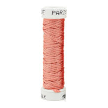 a spool of peach silk thread on a white background