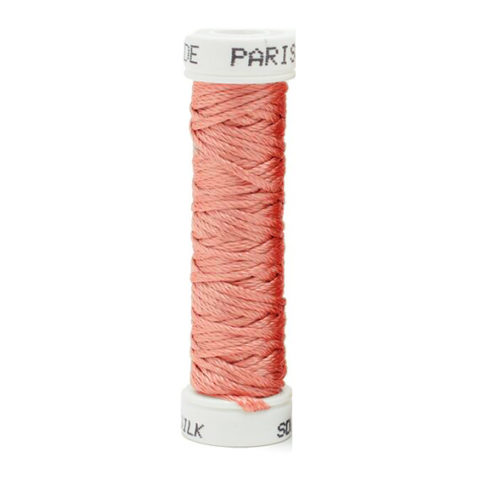 a spool of peach silk thread on a white background