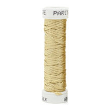 a spool of pale yellow green silk thread on a white background