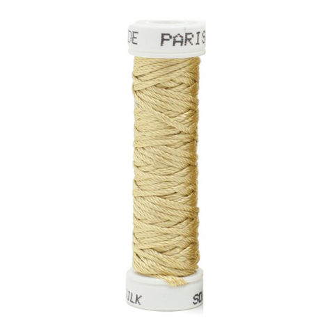 a spool of pale yellow green silk thread on a white background