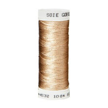 a spool of tan silk thread on a white background