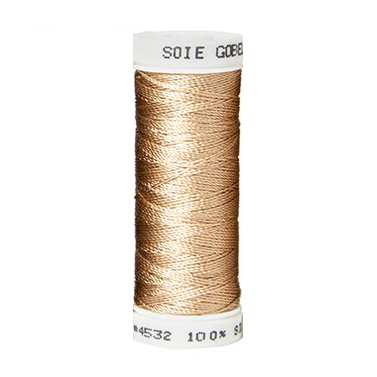 a spool of tan silk thread on a white background