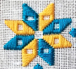 blue and yellow Ukrainian star embroidered on white linen in blue and yellow