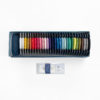 Sashiko thread bobbins in 29 colors arranged in a rainbow and a small dark blue pincushion inside the bottom of a blue paper gift box. Displayed below is a package of 4 assorted sashiko needles