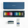 Sashiko thread bobbins in 29 colors arranged in a rainbow inside the bottom of a blue paper gift box. Displayed above is the lid of the box, which has the word "sashiko" stamped in white. Displayed below is a dark blue pincushion inside grey paper and package of 4 assorted sashiko needles