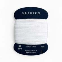 White sashiko thread on a navy blue cardboard bobbin