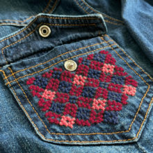 diamond lattice tatreez pattern stitched onto the pocket of a denim shirt