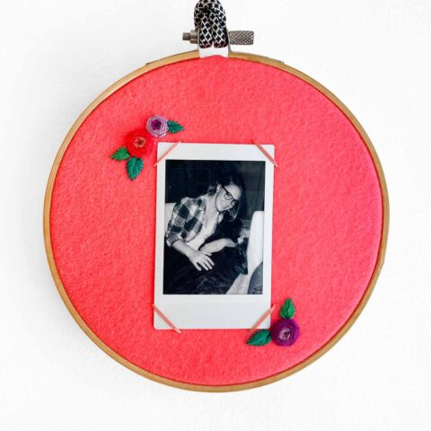 embroidered photo frame on bright pink felt displaying an instant grayscale portrait