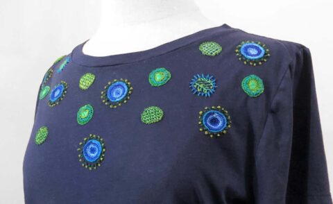 a navy tshirt embroidered with circular designs around the yoke in blue and green