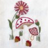 mushrooms, flowers, and acorns embroidered on a white linen tea towel