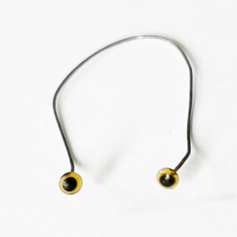 two tiny amber glass eyes connected by a thin wire